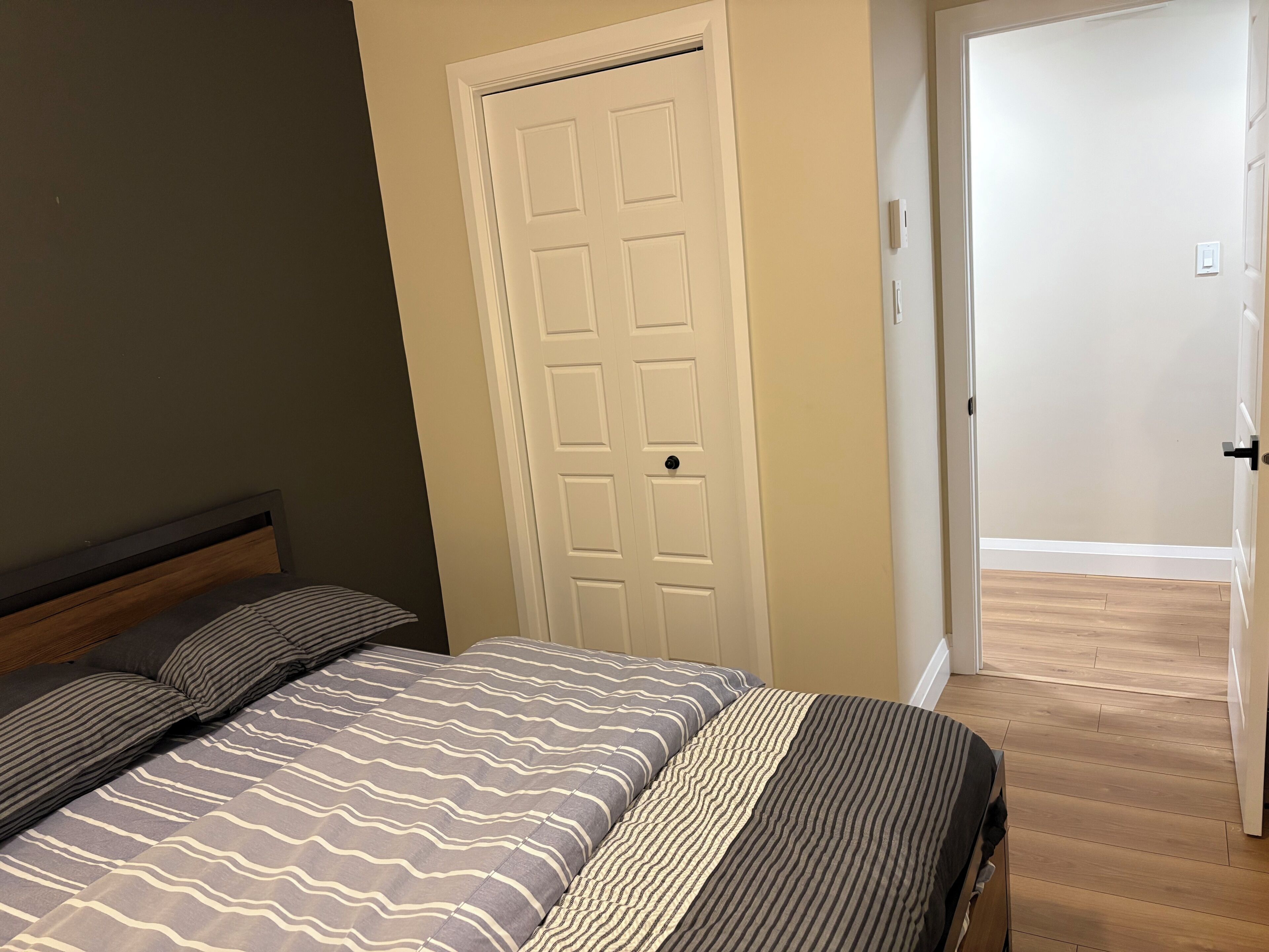 Ein Schlafzimmer mit Bett, Tür und Flur.