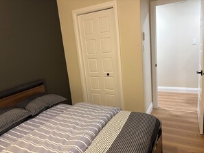 A bedroom with a bed, a door, and a hallway.