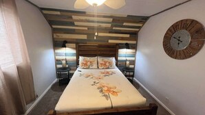 Una camera da letto con un letto, una testiera in legno, una sveglia a parete e una ventola a soffitto.