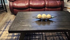 Un soggiorno con un divano in pelle marrone, un tavolino da caffè in legno scuro con una ciotola decorativa e un tappeto a motivi.