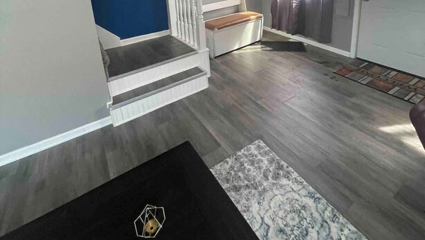 Un soggiorno moderno con una scala, un televisore a schermo piatto e un tappeto decorato.