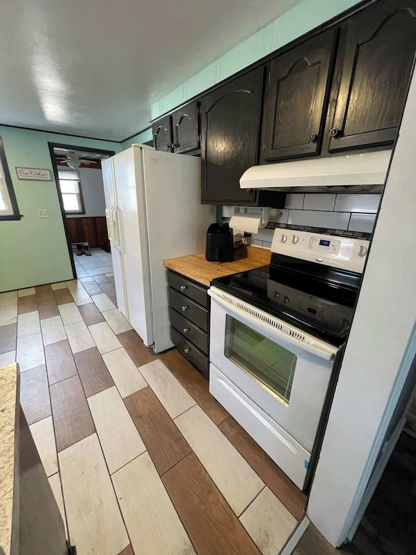 A kitchen with a refrigerator, stove, and cabinets.