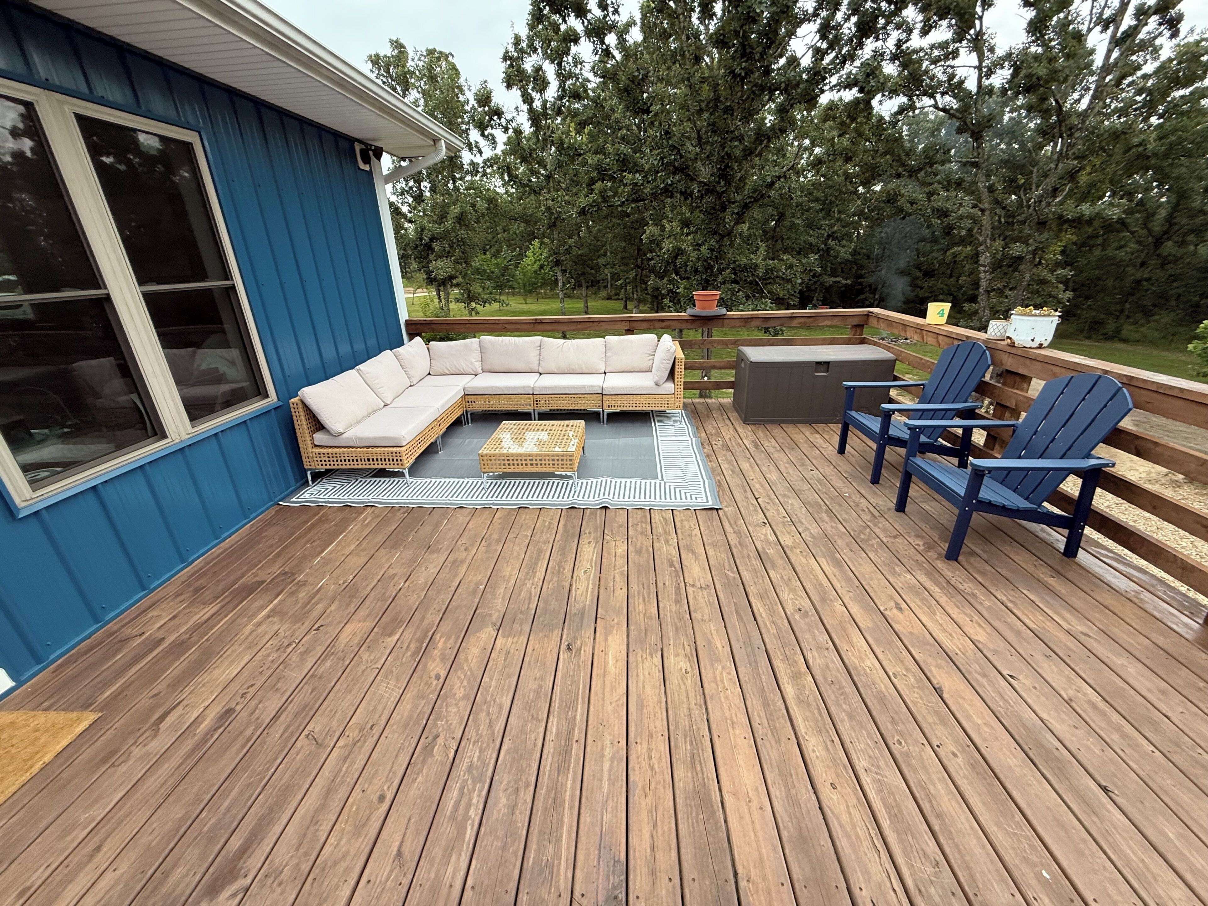 Une terrasse dotée d’un canapé modulable, de deux fauteuils Adirondack et d’une petite table.