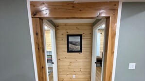 A hallway with wooden flooring, a framed picture on the wall, and a couch in the foreground. - 6BR Ozark Retreat on 10 Private Acres - Fire Pits, Game Room & Patio (Saint James)