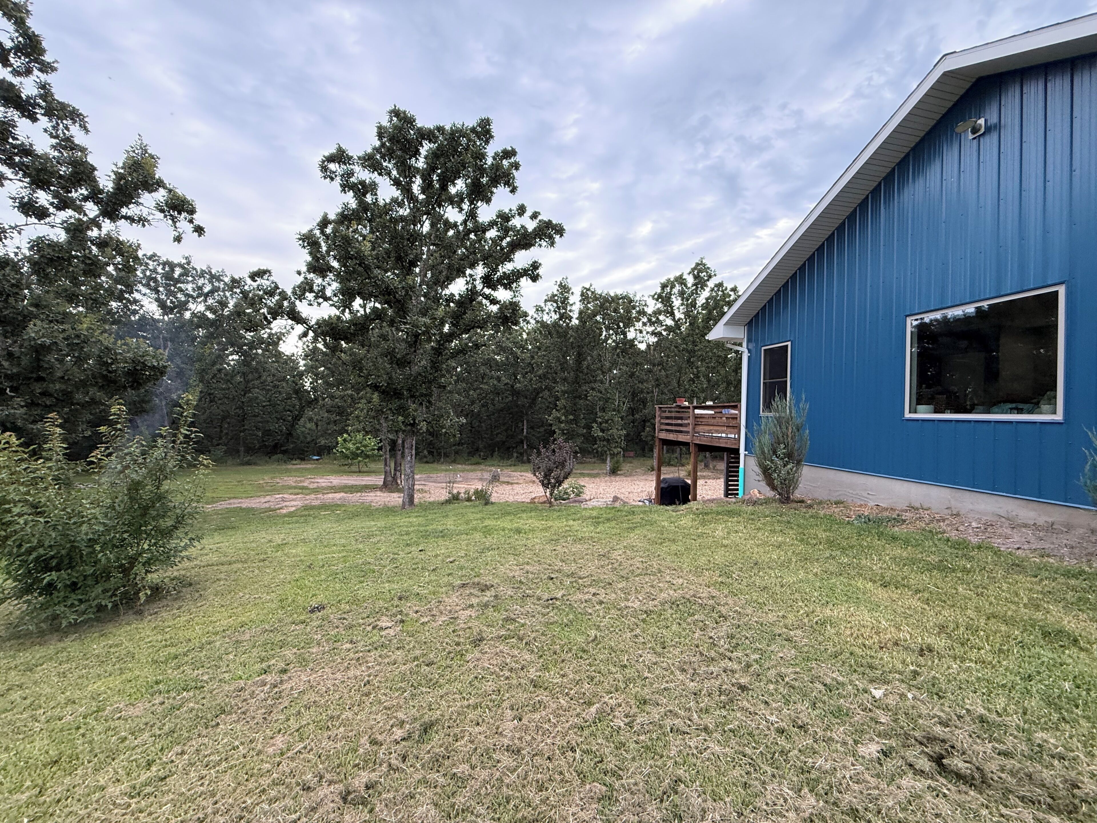 A blue building with a deck and a large tree in the yard.