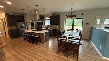 Una cocina moderna con una isla central, sillas de madera y una mesa de comedor.