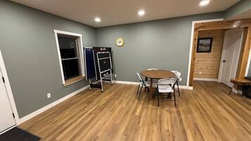 Una habitación con piso de madera, una mesa redonda con sillas, una pizarra y una puerta con panel de madera.