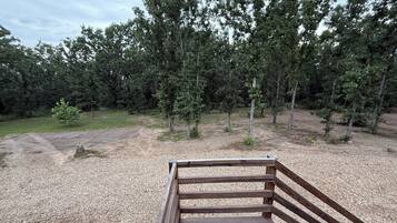 A wooden deck with a gravel path leading to a forested area.