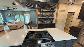 A kitchen with a central island, stainless steel appliances, and a blue-tiled backsplash. - 6BR Ozark Retreat on 10 Private Acres - Fire Pits, Game Room & Patio (Saint James)