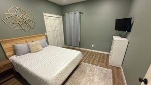 A bedroom with a bed, a wooden headboard, a white cabinet, a television, and a ceiling fan. - 6BR Ozark Retreat on 10 Private Acres - Fire Pits, Game Room & Patio (Saint James)