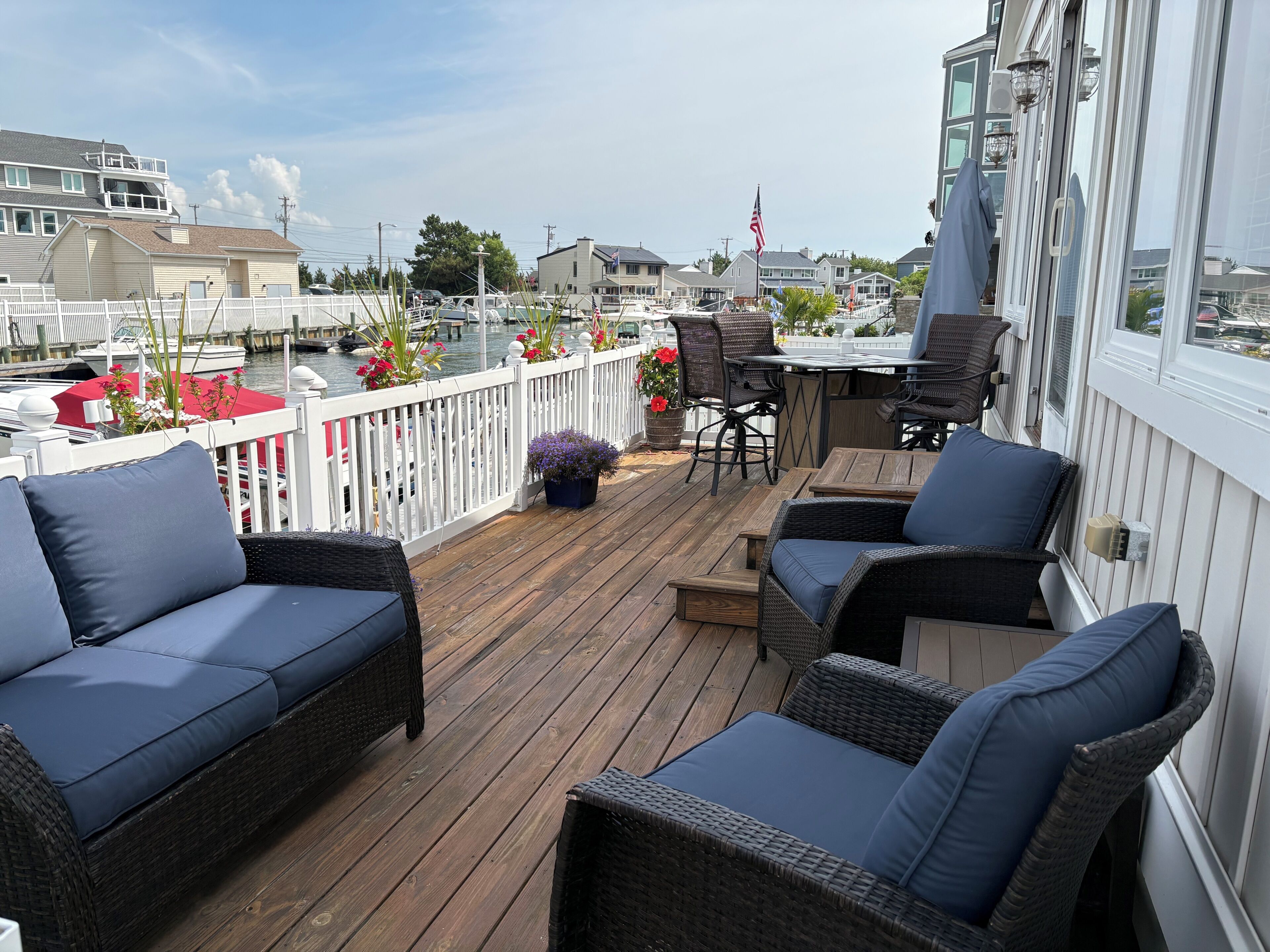A wooden deck with wicker furniture, a small table, and potted plants.