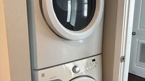 Eine übereinander gestellte Waschmaschine und Trockner mit Bedienfeld und Knöpfen.