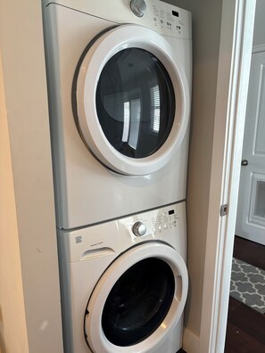 Eine übereinander gestellte Waschmaschine und Trockner mit Bedienfeld und Knöpfen.