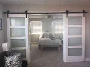 A bedroom with a bed, two windows with blinds, a ceiling fan, and a sliding door with frosted glass panels. - Sea View Harbor Bayfront with boat slip and jet ski docks.This 3-2 includes Pool (Longport)