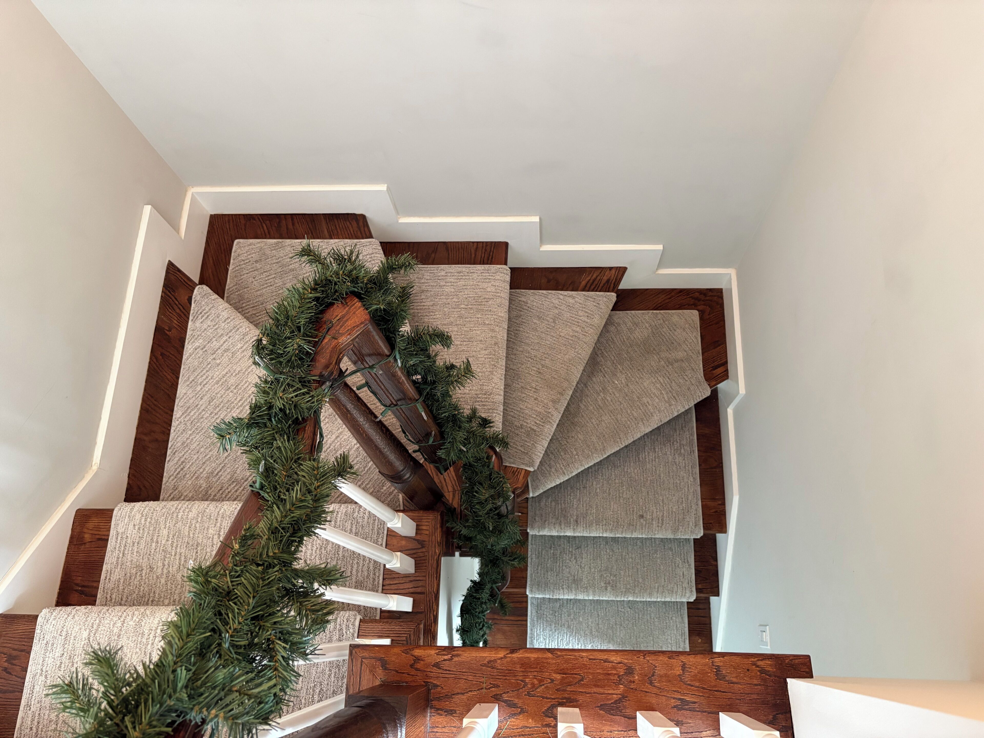 Un escalier avec une rampe en bois et des marches recouvertes de moquette.