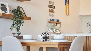 A dining area with a wooden table set for two, a potted plant, and a wall with decorative signs. - Refugio en el Mar Despierta frente al Caribe (Porlamar)