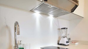A modern kitchen with a stainless steel sink, a built-in range hood, and a countertop with a blender. - Refugio en el Mar Despierta frente al Caribe (Porlamar)