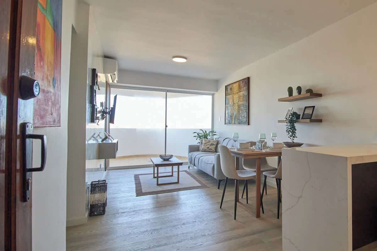 Ein modernes Wohnzimmer mit Sofa, Esstisch und Stühlen. Ein großes Fenster sorgt für natürliches Licht.
