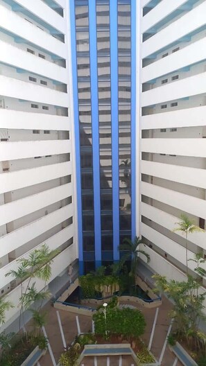 Ein mehrgeschossiges Gebäude mit einem zentralen Atrium, umgeben von Balkonen und Grünpflanzen.
