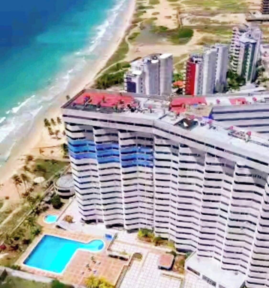 Een hoog hotel met zwembad en uitzicht op het strand.