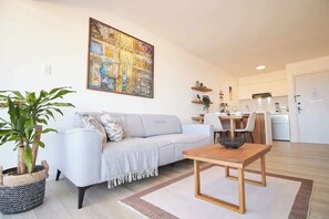 Een moderne woonkamer met een bank, een eettafel en een keuken op de achtergrond.