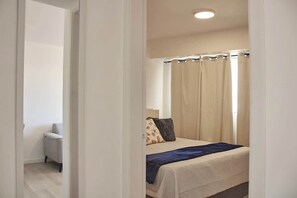 Ein Schlafzimmer mit einem Bett, einem Nachttisch und einem Fenster mit Vorhängen.