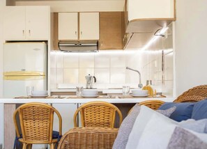 Une cuisine compacte avec des meubles blancs, un réfrigérateur en acier inoxydable et un robinet moderne.