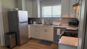 A compact kitchen with a refrigerator, sink, microwave, and stove.