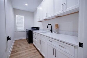 A kitchen with white cabinets, a black faucet, and a built-in oven. - The Endzone | 6BR Near UF & Shands Sleeps 14 (Gainesville)