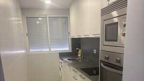 A compact kitchen with a washing machine, a sink, and a microwave. - Well-located apartment (Platja de l'Arenal)
