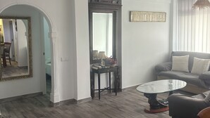 A living room with a sofa, a round coffee table, a mirror, and a decorative ceiling light fixture. - Well-located apartment (Platja de l'Arenal)