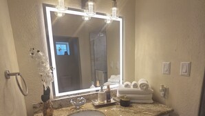 Uma casa de banho com um espelho grande, uma pia e uma cómoda com gavetas.