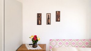 A bedroom with a wooden nightstand, a vase of flowers, and a bed with a floral-patterned headboard. - Room-singh Leite Holiday Home Cosy Room (Lisbon)