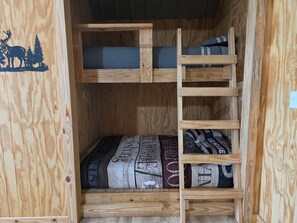 A bunk bed with a wooden frame and a patterned blanket.
