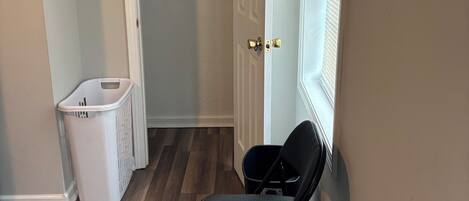 Un dormitorio con cama, una silla, un cesto de ropa y un armario con puerta.