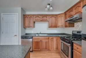 A kitchen with wooden cabinets, a granite countertop, a stove, and a dishwasher. - A 2-story, 3-bedrooms, 2.5 bathrooms with 3 hospitals that are 1 - 25 miles away (Lowville)