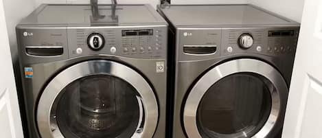A laundry area with two front-loading washing machines and a shelf above.