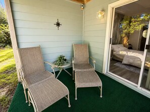 A covered patio with two wicker chairs, a small table with a glass, and a compass decoration on the wall. - Family Getaway Near Disney • Pool & Hot Tub (Kissimmee)