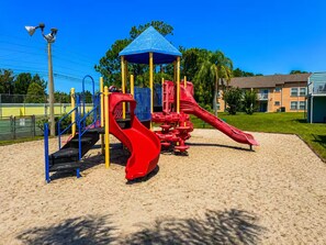 A playground with a red slide and a blue climbing structure. - Family Getaway Near Disney • Pool & Hot Tub (Kissimmee)