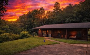 A log cabin with a porch, a bench, and a small table.