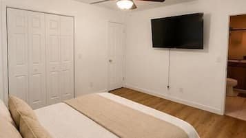 Bright, cozy bedroom with TV, ceiling fan, and en suite bath