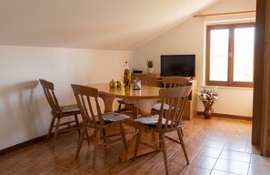 A dining area with a wooden table and chairs, a television, and a window with natural light. - Apartment Duka "for 5" - 100m sandy beach + panoramic sea view + AirCon. & WiFi. (Lumbarda)