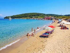 A beach with clear water, a sailboat, and people enjoying the shore. - Apartment Duka "for 5" - 100m sandy beach + panoramic sea view + AirCon. & WiFi. (Lumbarda)