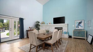 Un comedor con una mesa, sillas, una chimenea, un televisor y un armario.