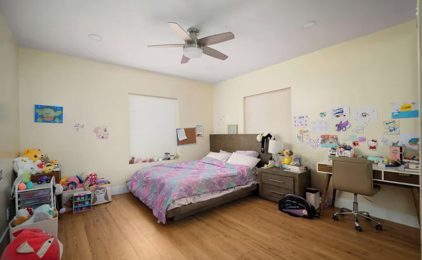 A bedroom with a bed, desk, chair, and various personal items.