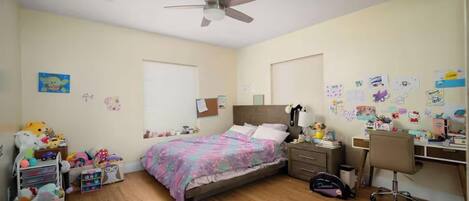 A bedroom with a bed, desk, chair, and various personal items.