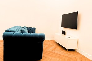 A room with a dark blue sofa, a white cabinet, and a flat-screen TV mounted on the wall. - Dimora Smeraldo - an exclusive apartment just 10 minutes from the Amalfi Coast (Cava de' Tirreni)