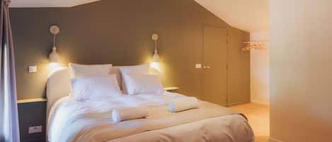 A bedroom with a bed, bedside lamps, a wardrobe, and a hanging light fixture.