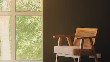 Una habitación con un ventanal grande, una silla de madera y una pared oscura.