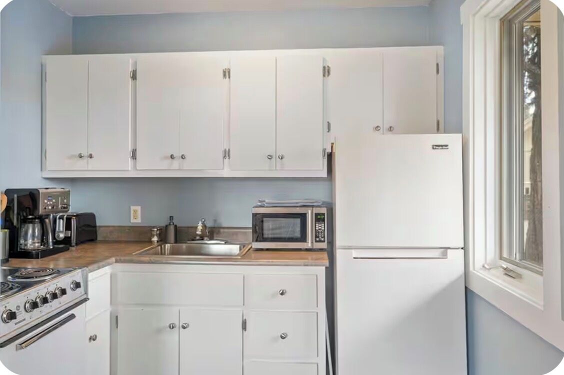A kitchen with white cabinets, a microwave, a stove, and a refrigerator.